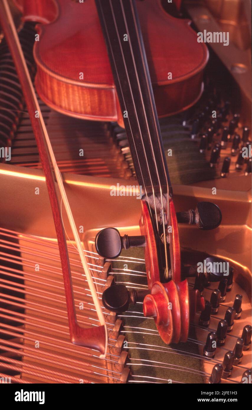 A  old Violin and bow laying on a Piano Stock Photo