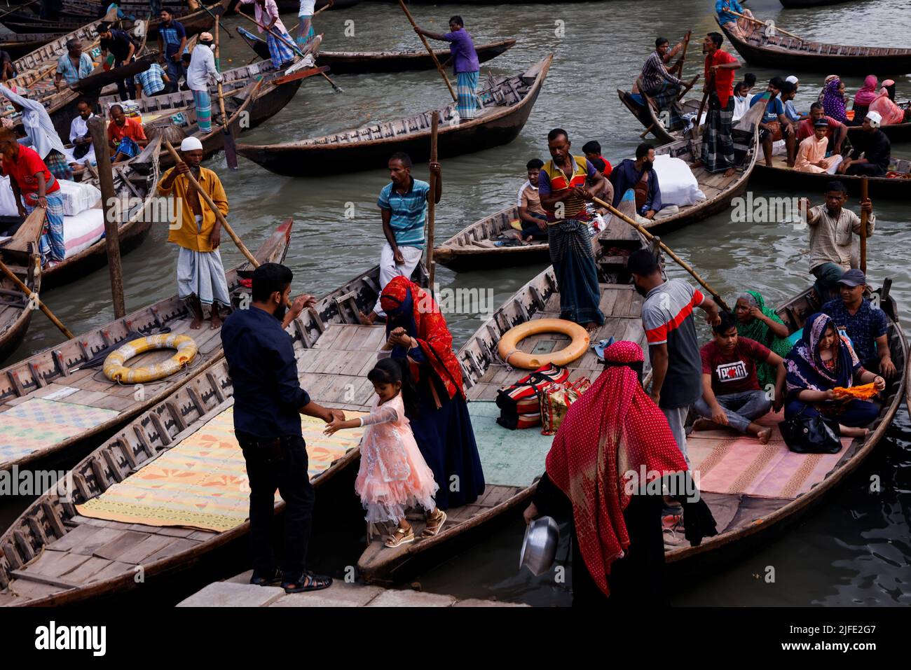 Parents help their child to get off from boat after crossing the river Buriganga in Dhaka, Bangladesh, July 2, 2022. REUTERS/Mohammad Ponir Hossain Stock Photo