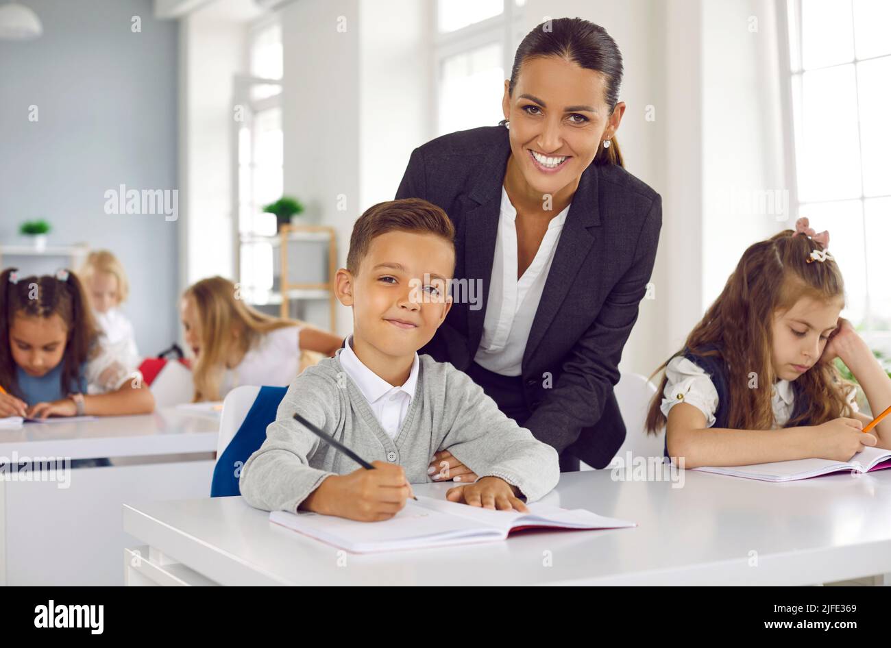 Portrait of happy, smiling school teacher and student during class in the classroom Stock Photo