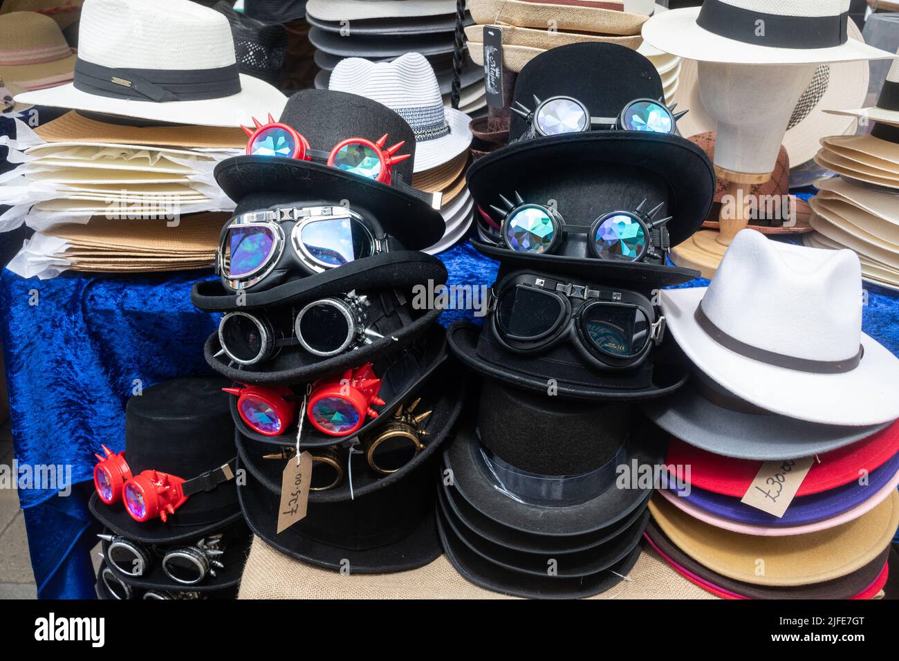 Display of hats for sale on a market stall during Winchester Hat Fair event, including black steampunk hats with goggles or glasses, England, UK Stock Photo