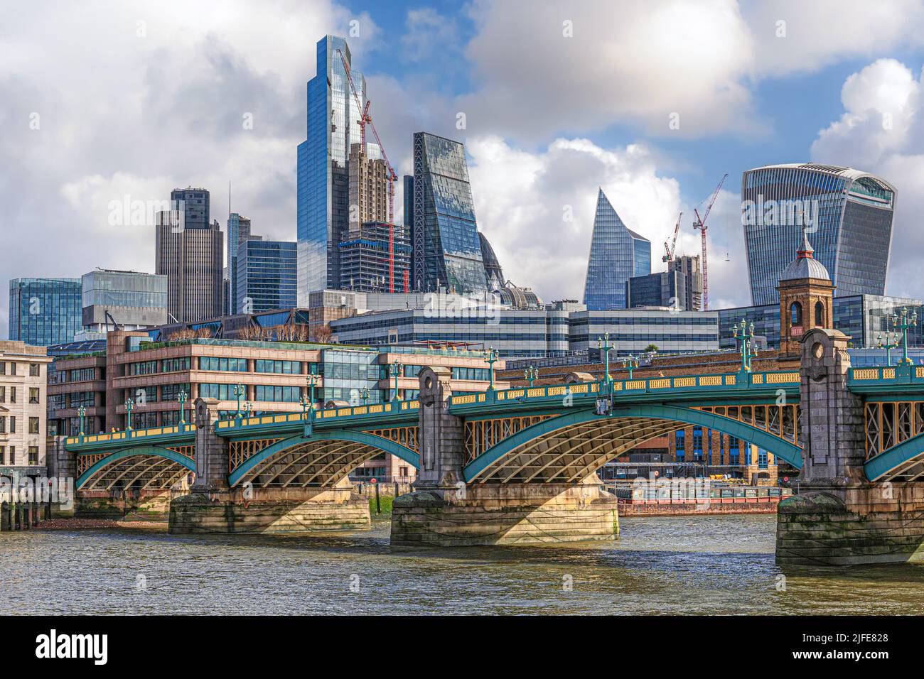 Colourful Southwark Bridge spanning the River Thames in London with Canary Wharf behind Stock Photo