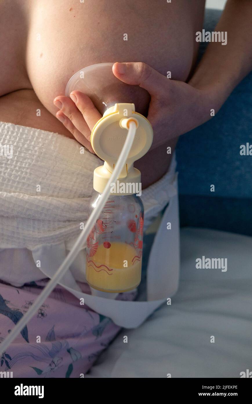 Close up of woman holding baby bottle and breast pump pumping milk for her baby Stock Photo