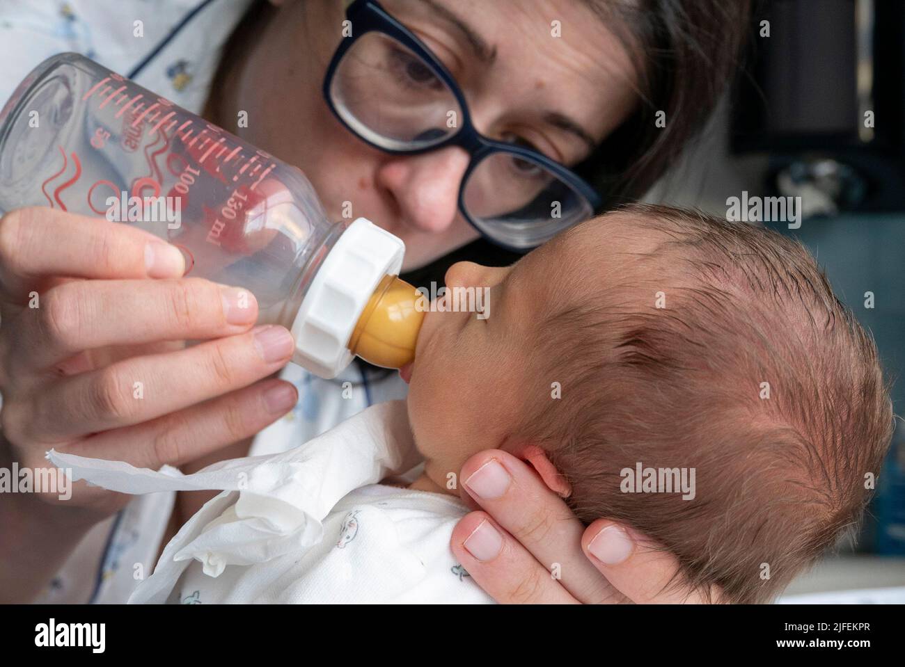 Young woman feeding a newborn premature baby with a nursing bottle Stock Photo