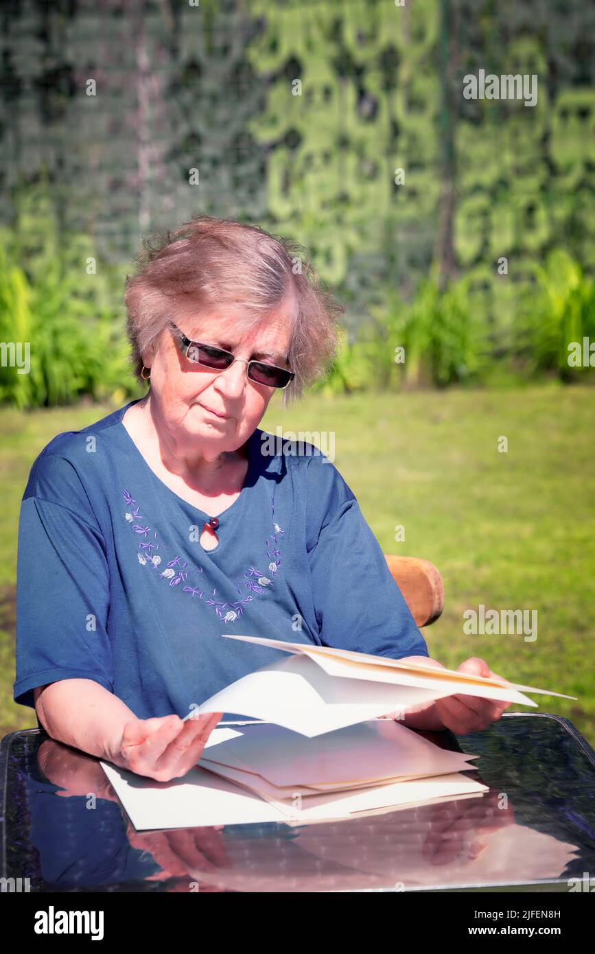 Elderly woman sorting through papers while sitting outdoor. Stock Photo