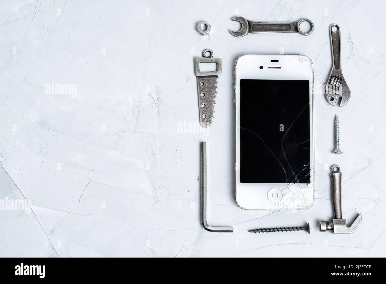 View of Cracked screen mobile phone with a set of repair tools on a concrete ...