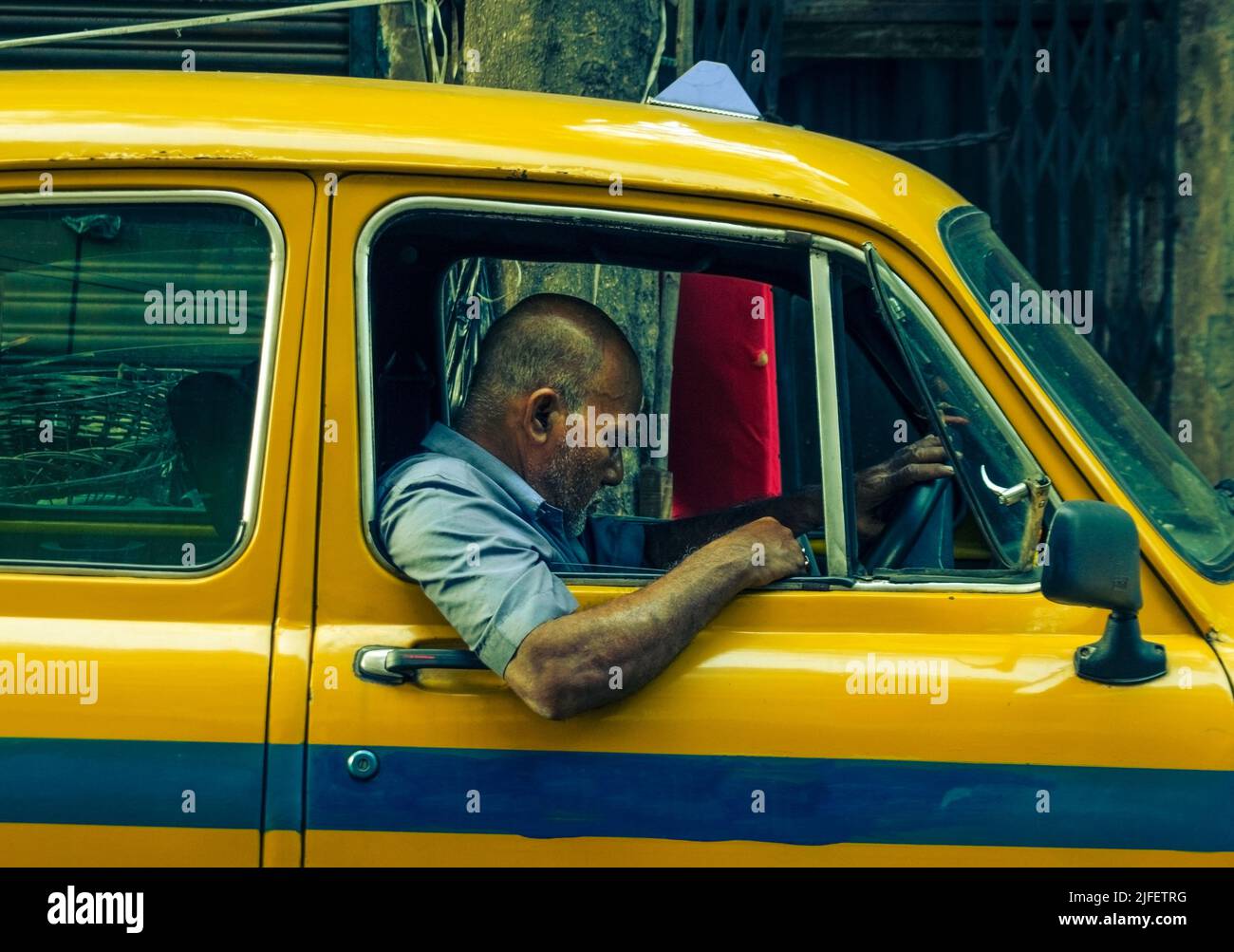 Kolkata, India - 26 June, 2022: A man sitting inside the iconic yellow taxi of Kolkata with a disappointed expression. Selective Focus. Stock Photo