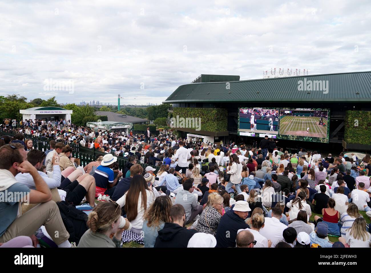 Spectators on The Hill watch the big screen as Stefanos Tsitsipas players Nick Kyrgios during their Men's Singles third round match during day six of the 2022 Wimbledon Championships at the All England Lawn Tennis and Croquet Club, Wimbledon. Picture date: Saturday July 2, 2022. Stock Photo