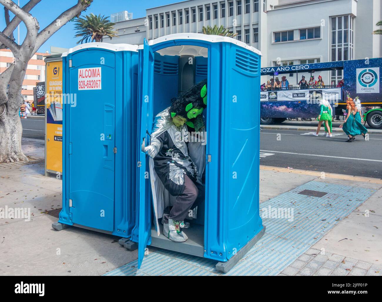 Las Palmas, Gran Canaria, Canary Islands, Spain. 2nd July, 2022. Thousand of people in fancy dress enjoying the Las Palmas Carnival street parade in blazing sunshine. PICTURED: A tight squeeze in the portable toilet for a man wearing a two head hat. Credit: Alan Dawson/ Alamy Live News. Stock Photo