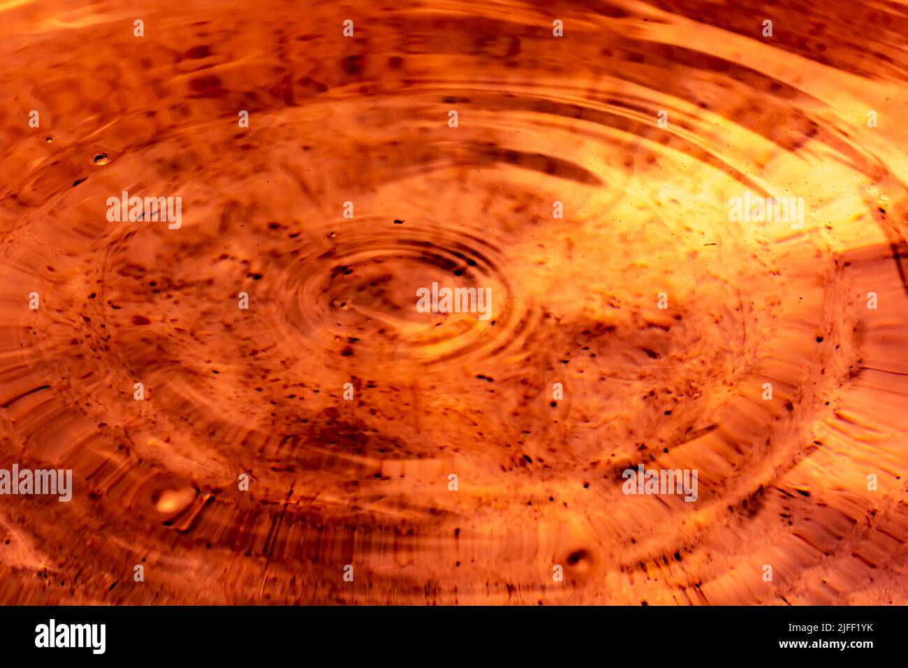 Small Ripple Circles and small ripples on orange-brown liquid. Backdrop Stock Photo ...