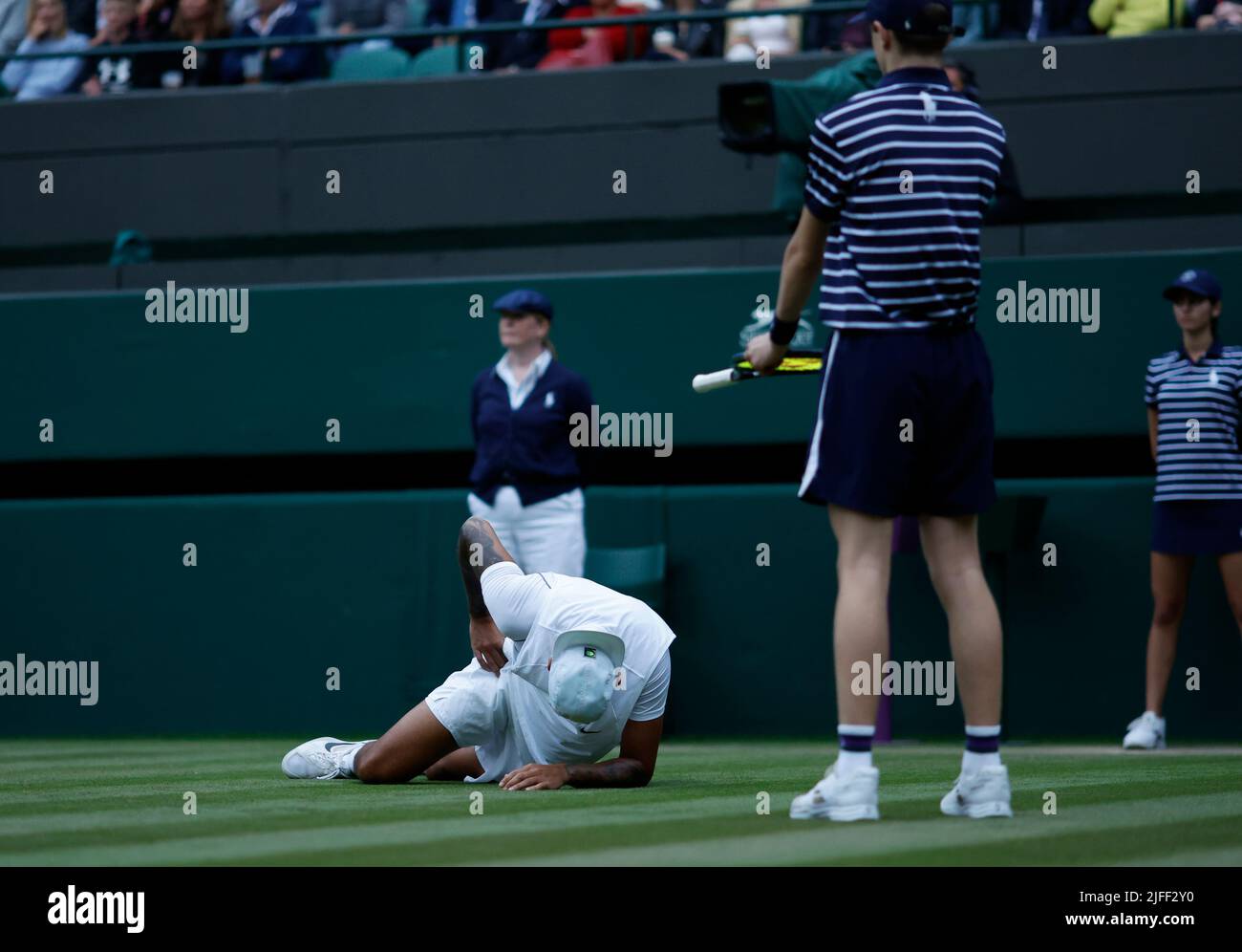 Nick Kyrgios goes down clutching his hip during his Men's Singles third round match against Stefanos Tsitsipas during day six of the 2022 Wimbledon Championships at the All England Lawn Tennis and Croquet Club, Wimbledon. Picture date: Saturday July 2, 2022. Stock Photo