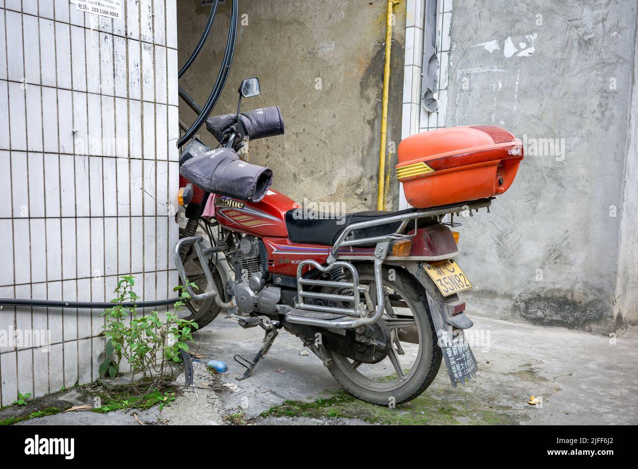 A red motorcycle parked between the buildings Stock Photo - Alamy