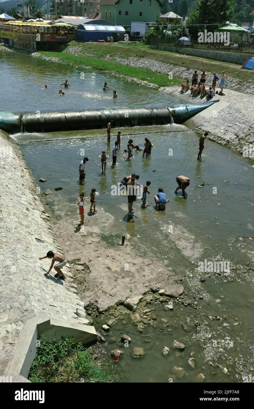 gypsy community cooling off and catching small fish by the hands in the shallow waters of the Bjelica river in Guca, Serbia Stock Photo