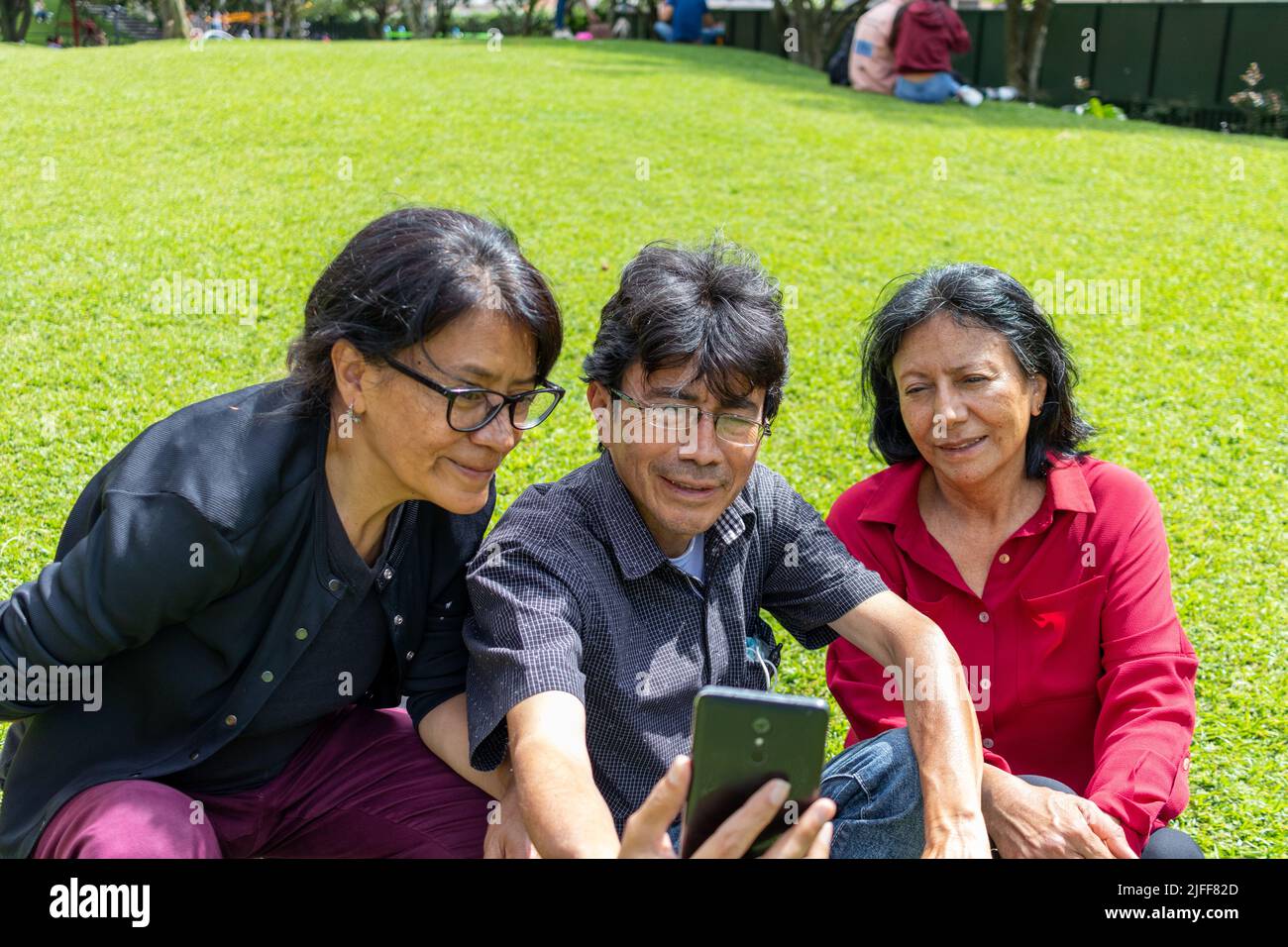 Group of middle aged latin friends taking a selfie and having fun in a park Stock Photo