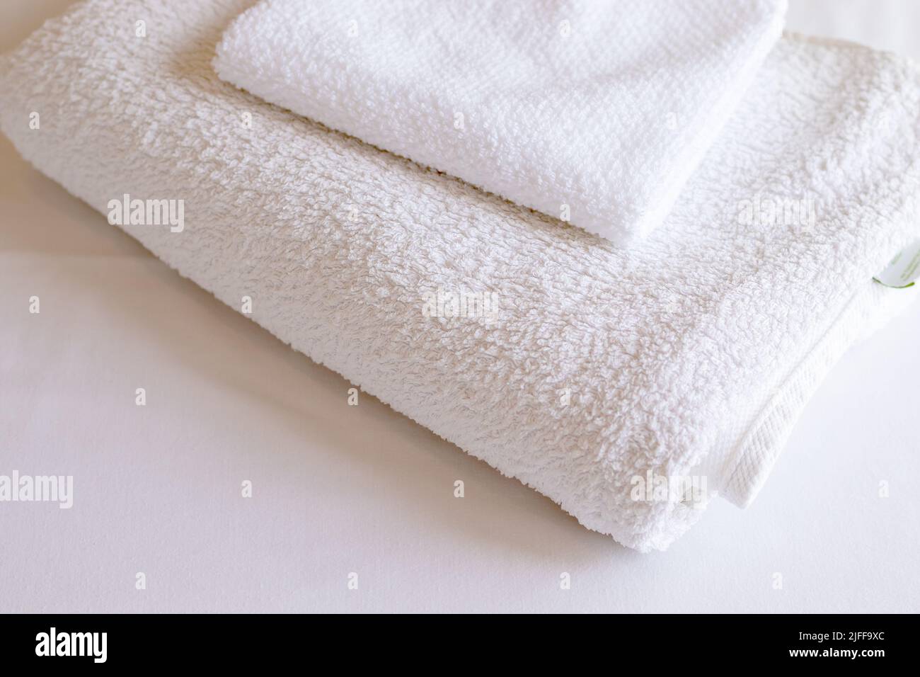 White folded clean towels on the hotel bed, Cleaning, laudry and washing towels at home. Stock Photo