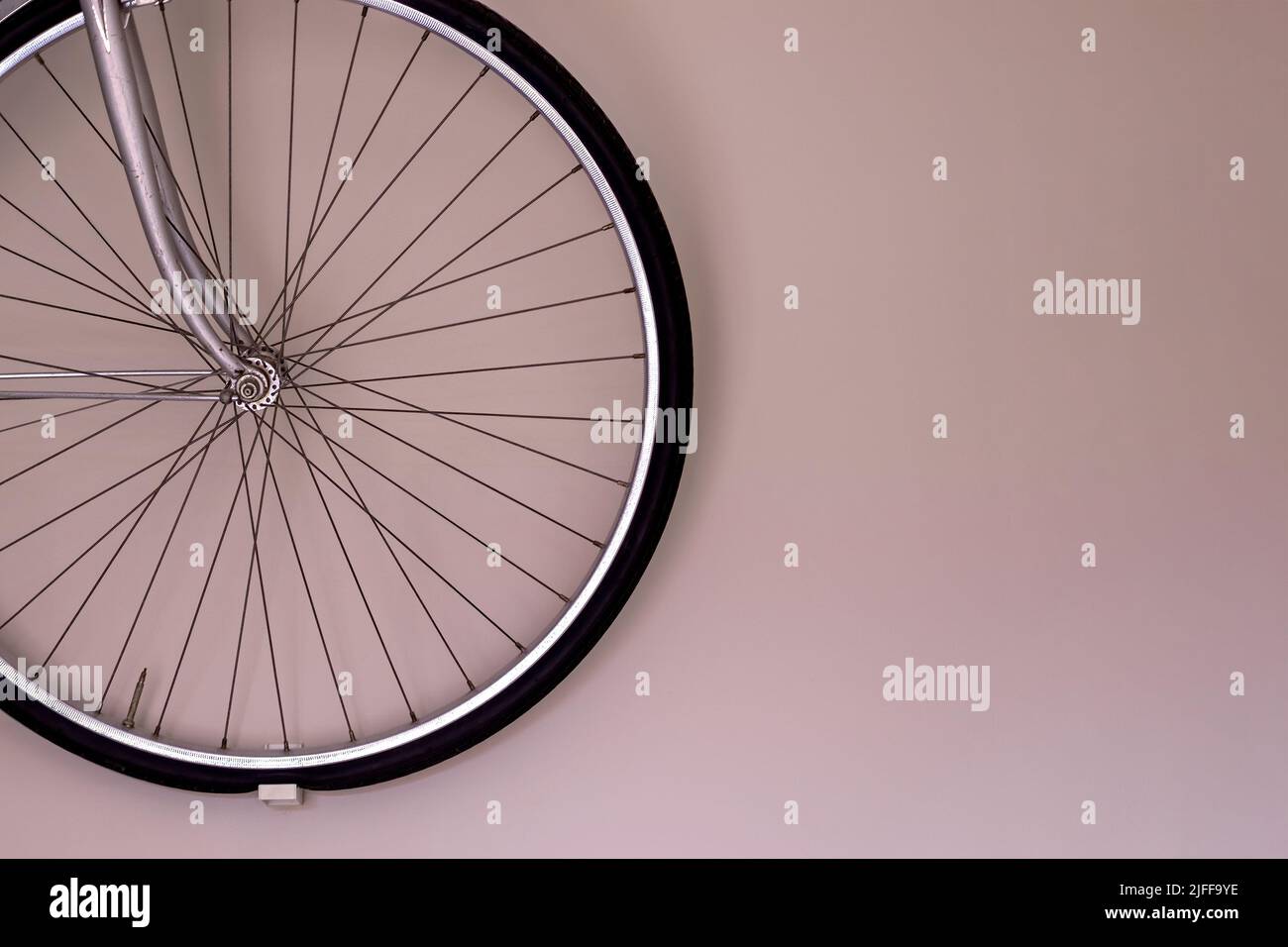 Bicycle wheel hanging on the wall with copy space. Wall mounted bike