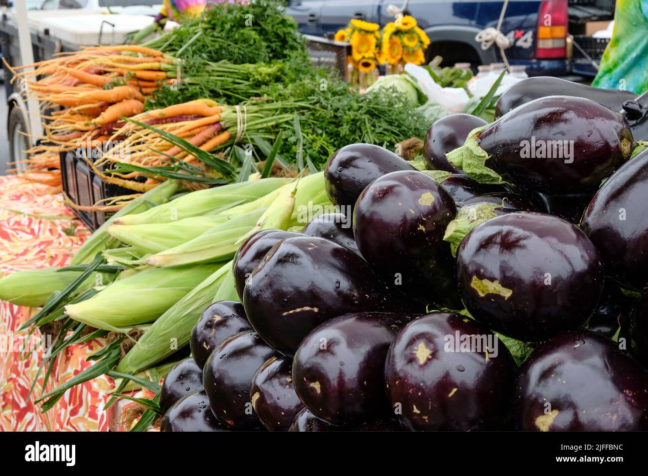 Fresh corn, eggplant and carrots being sold at a fresh vegetable and produce stand by a local farmer at the Montgomery Alabama farmers market. Stock Photo