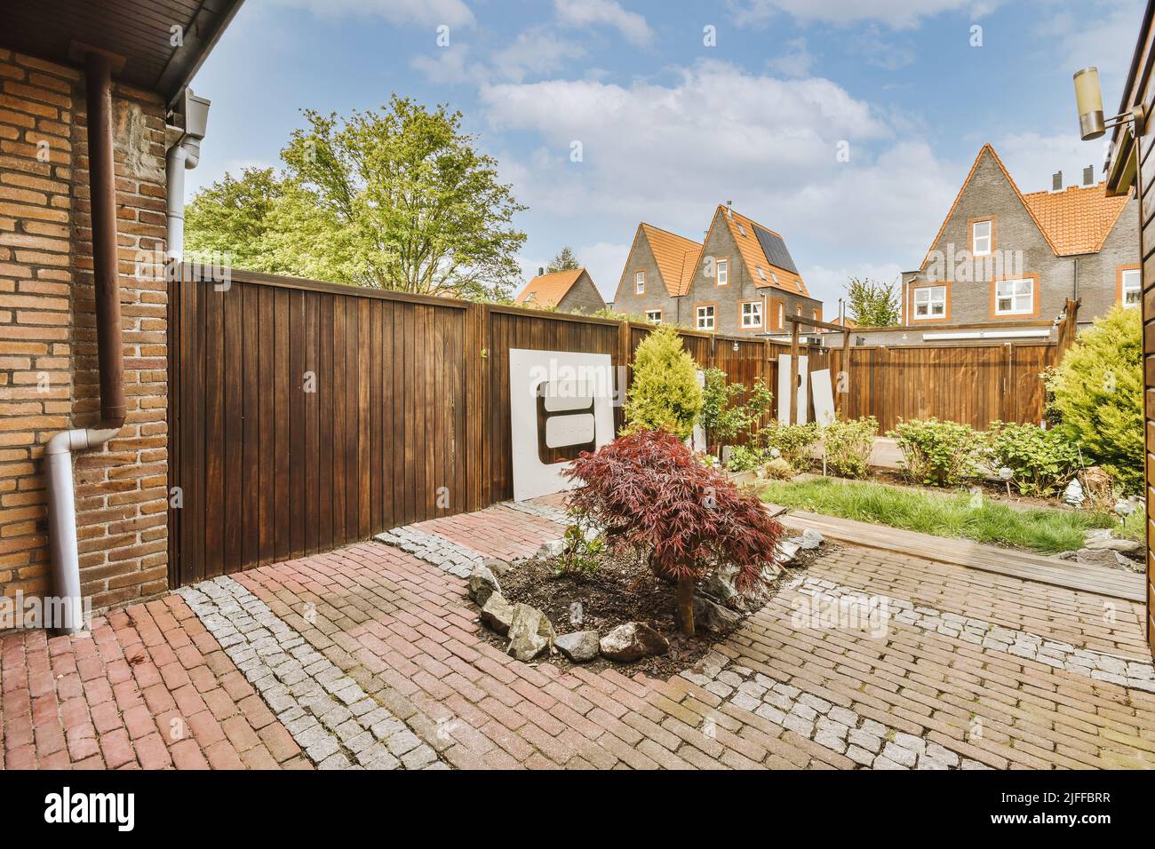 Neat courtyard of a modern house, with garden tiles, lawn, shrubs and ...
