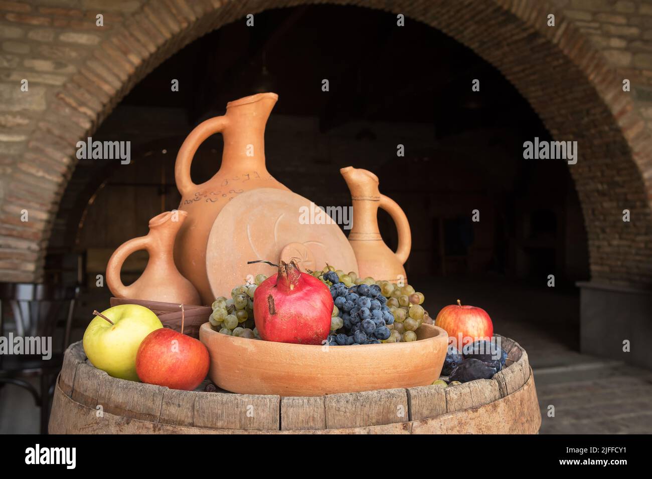 Serving barrel with clay jugs and fruits at the winery in Georgia Stock Photo