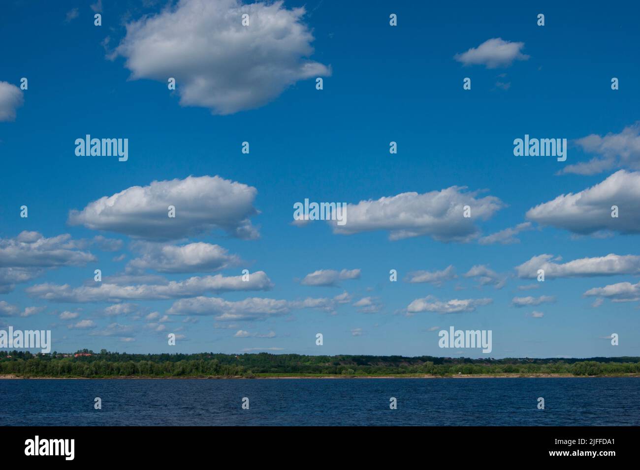 Deep cold ryokana in the north of Russia. The seasons are summer. A sandy beach with green bushes growing on it. White clouds in the blue sky - Stock Image