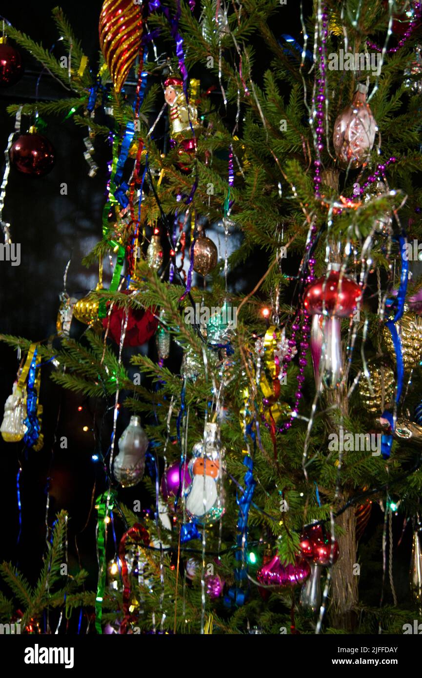 The holiday is a new year or Christmas, in the photo a live fir tree is decorated with toys, tinsel and beads. Retro. - Stock Image