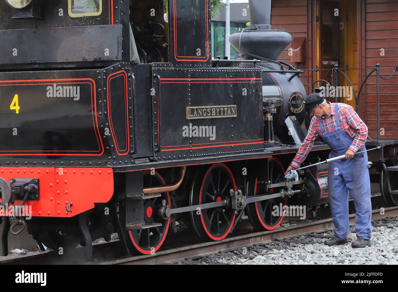Uppsala, Sweden - July 2, 2022: A narrow-gauge old steam locomotive in museum traffic is lubricated by the railway staff at Uppsala Eastern station. Stock Photo