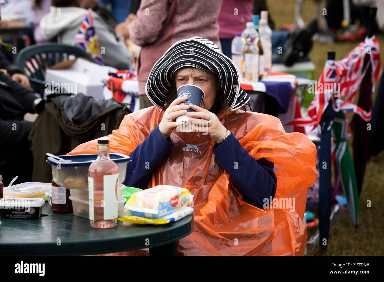 Woodstock, Oxfordshire, UK. 2nd July 2022. Woman drinking coffee in disposable rain poncho. Battle Prom Picnic Concerts. Blenheim Palace. United Kingdom. Credit: Alexander Caminada/Alamy Live News Stock Photo