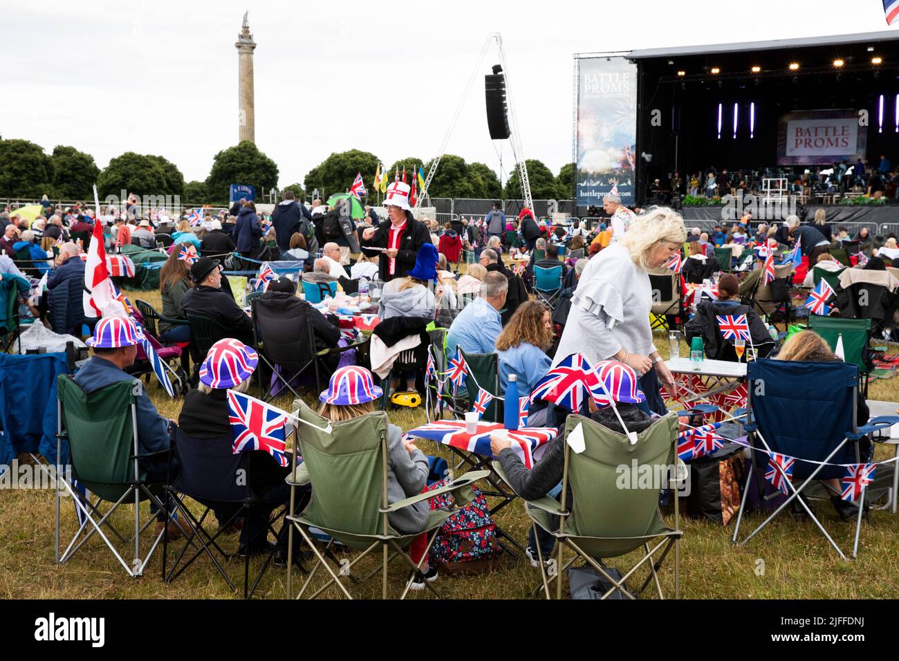 Woodstock, Oxfordshire, UK. 2nd July 2022. Audience seated in camping chairs with Untion Jack bowler hats. Battle Prom Picnic Concerts. Blenheim Palace. United Kingdom. Credit: Alexander Caminada/Alamy Live News Stock Photo
