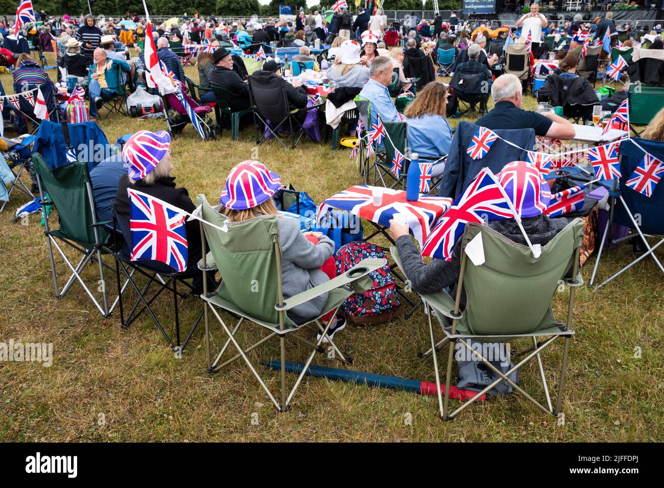 Woodstock, Oxfordshire, UK. 2nd July 2022. Audience seated in camping chairs with Untion Jack bowler hats. Battle Prom Picnic Concerts. Blenheim Palace. United Kingdom. Credit: Alexander Caminada/Alamy Live News Stock Photo