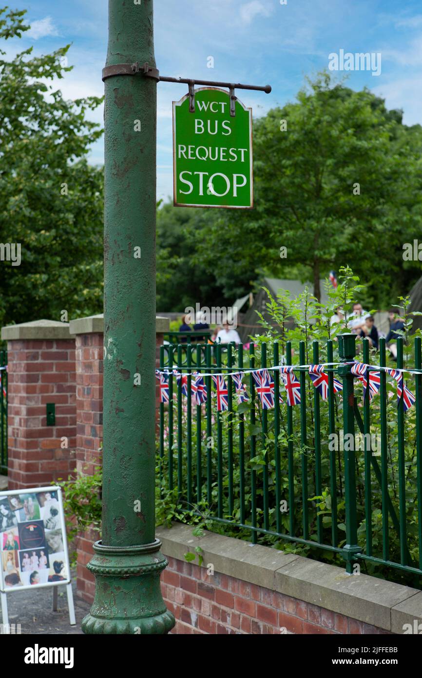 green bus stop on a green lamp post Stock Photo