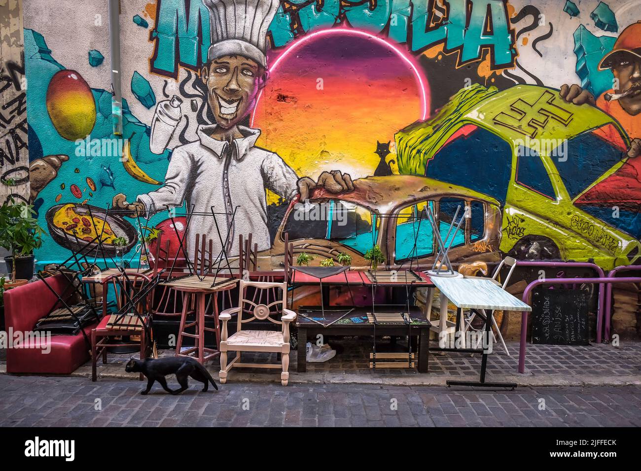 Marseille, France, May 2022, view of some chairs and tables piled up in front of a mural in Le Panier district Stock Photo