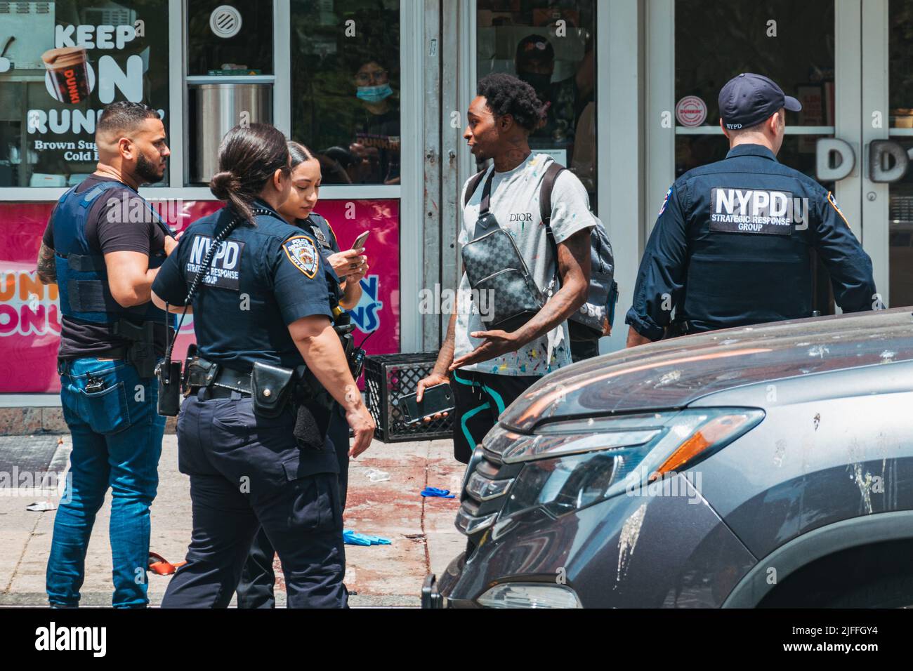July 2, 2022: NYPD officers speak with a man in front of the scene of a shooting in Manhattan's Lower East Side, New York Stock Photo