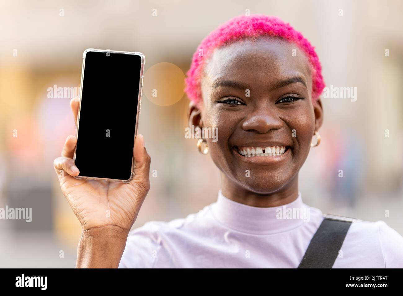 Afro woman with toothy smile showing the screen of mobile Stock Photo ...