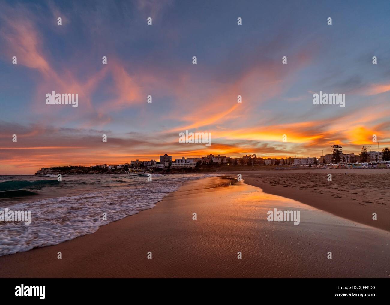 Beautiful colourful skies as the sun rises over the world famous Bondi Beach in Sydney Australia. Looking South over the deserted sand is magical Stock Photo
