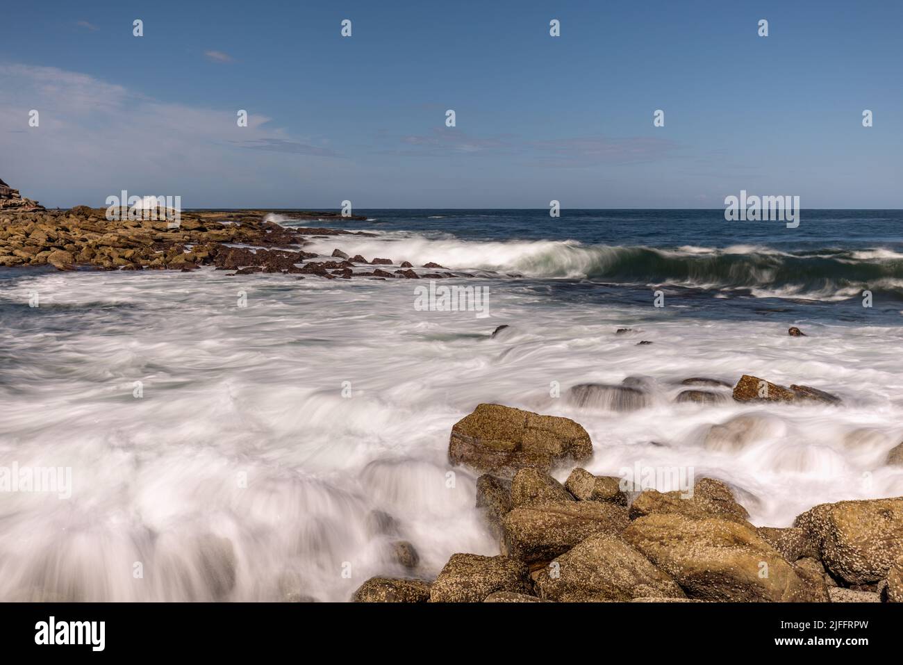 Long exposure landscape - silky sea water washing into rocks and breaking waves in Clovelly, Randwick, Sydney, on the Australian coast. Stock Photo