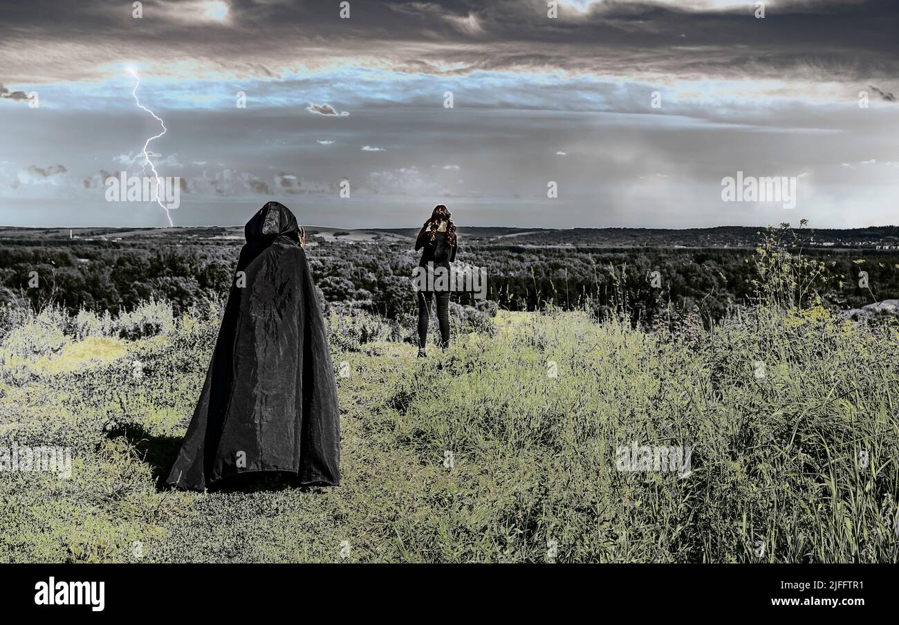 woman in a black raincoat with a hood approaches a young girl who is ...