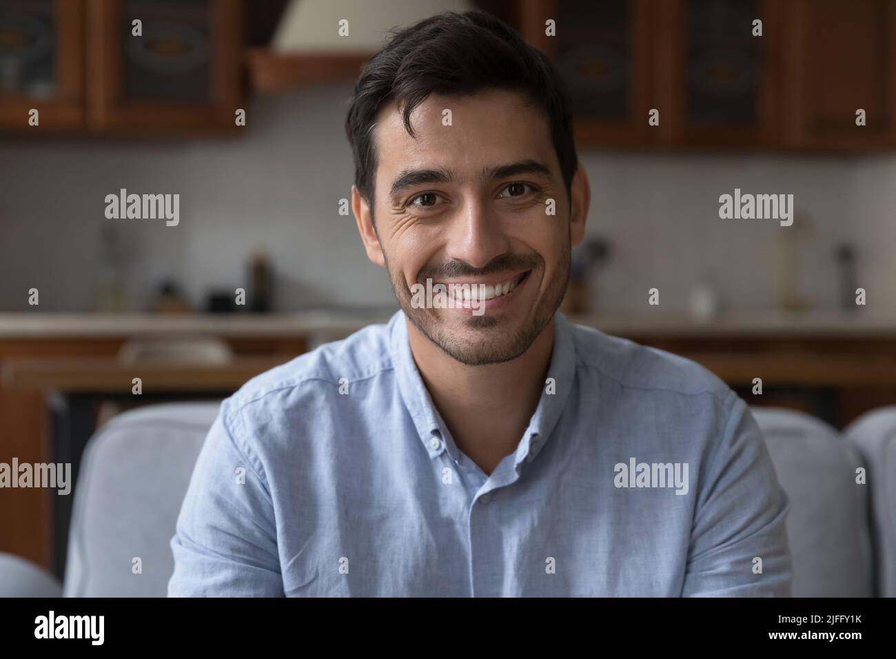 Hispanic man sit on sofa at home look at camera Stock Photo