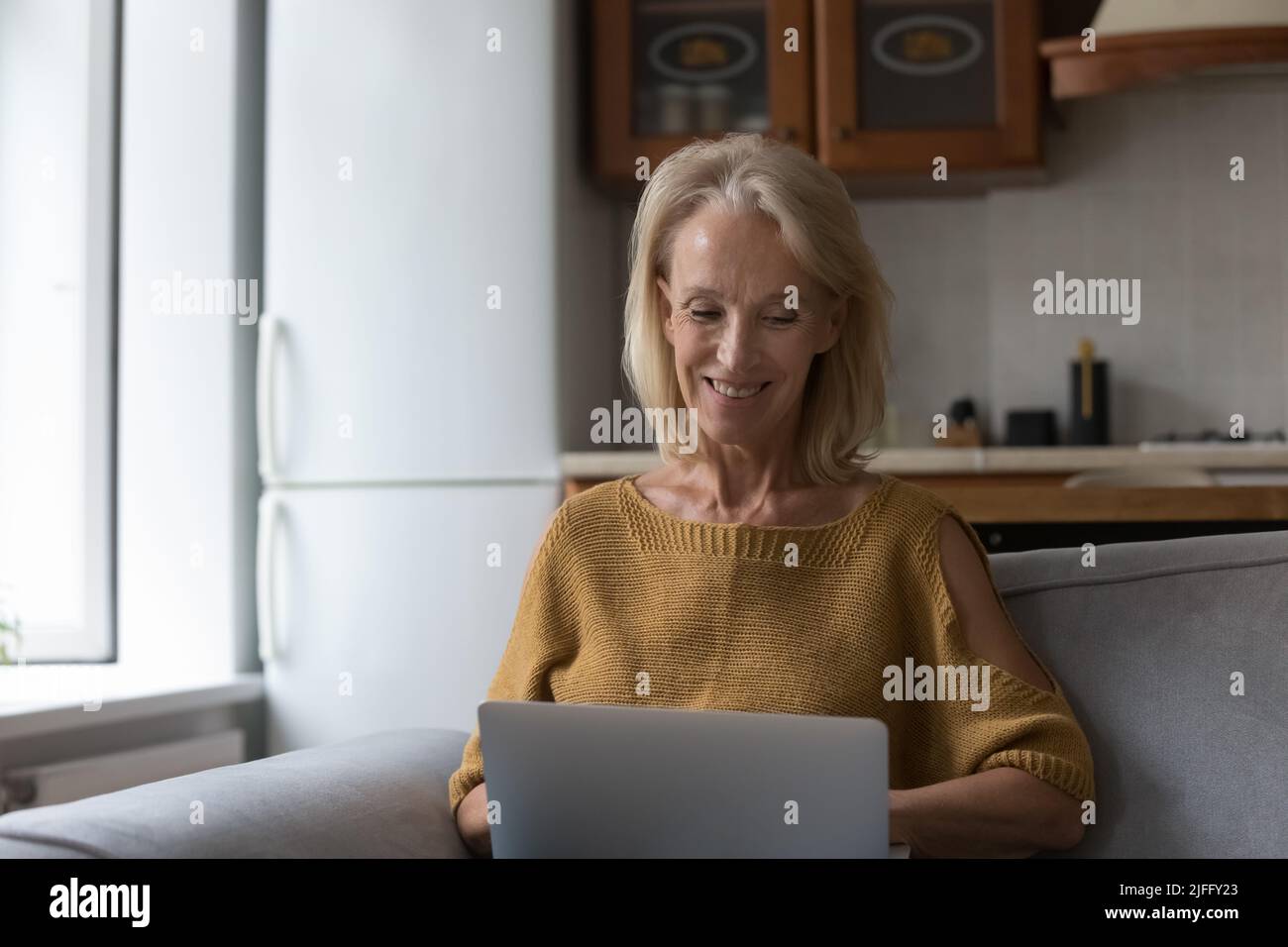 Smiling older woman using laptop at home Stock Photo