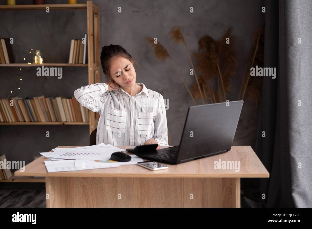 Business woman with neck ache, young woman suffering from neck pain in home office Stock Photo