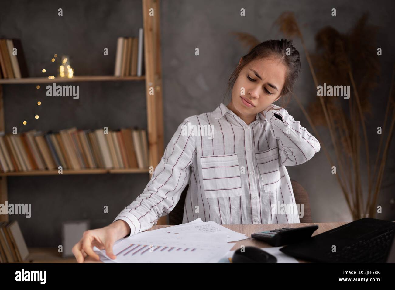 Young Hispanic woman suffering from neck pain in home office Stock Photo