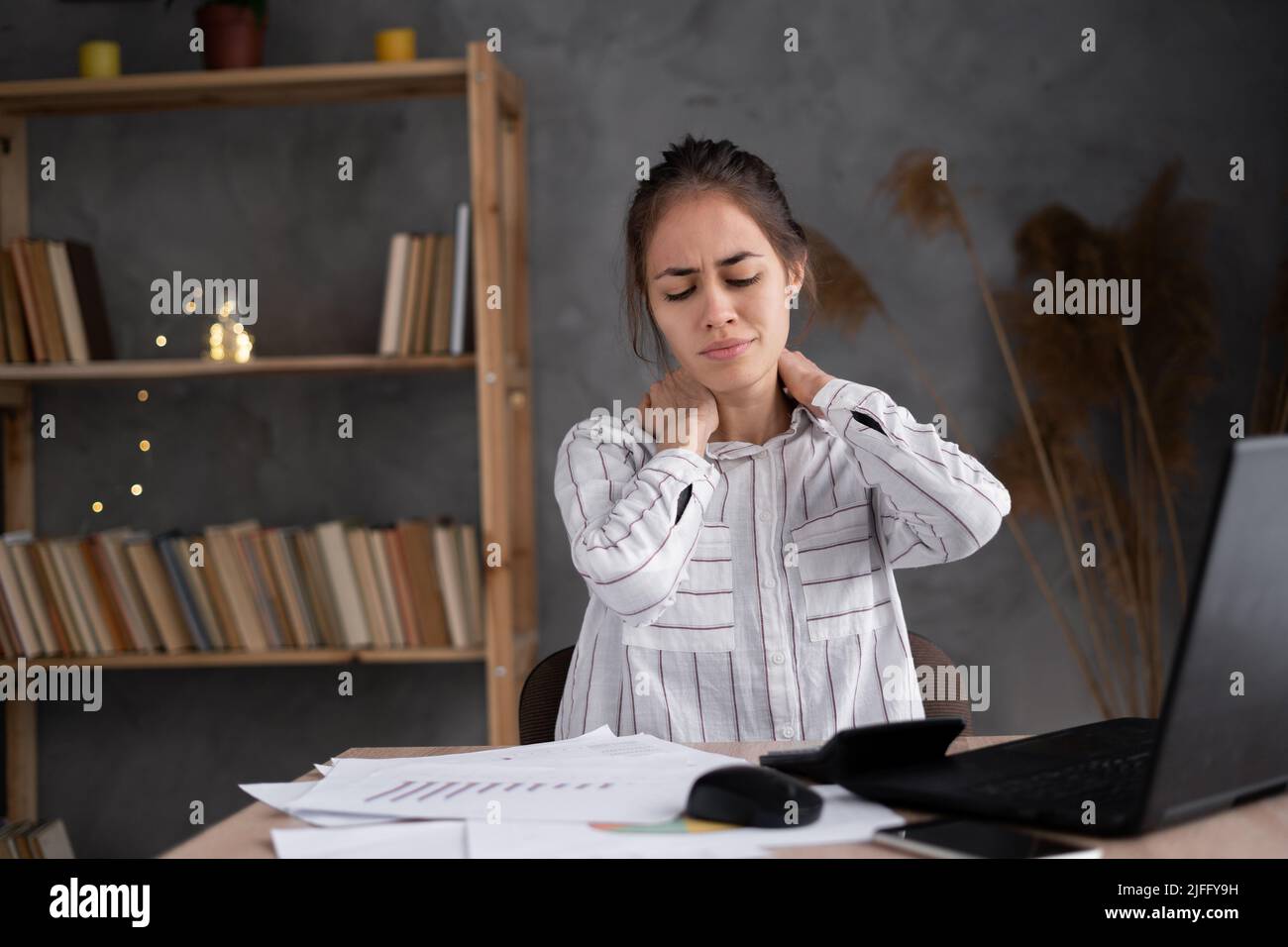 tired young woman rubbing her stiff neck massaging tense muscles, incorrect posture and sedentary work, fibromyalgia, incorrect posture Stock Photo