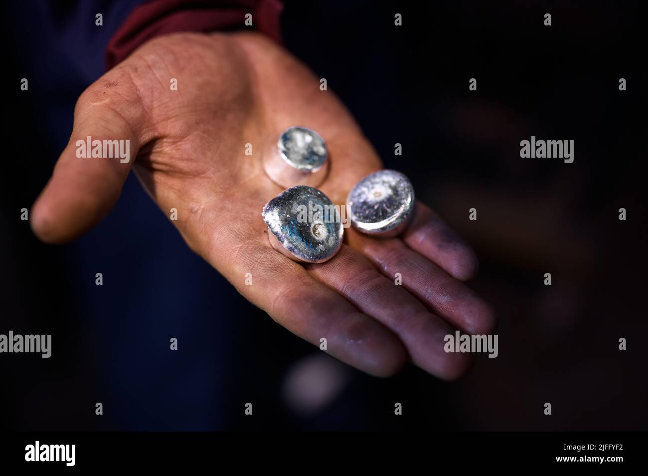 Small round bars of silver lie in the palm of your hand. Stock Photo