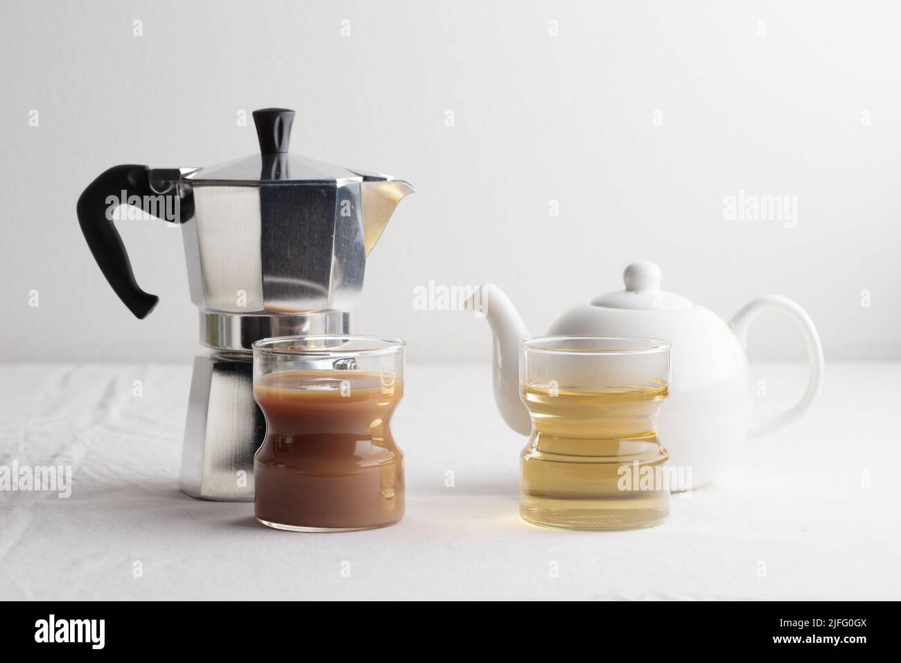 Coffee or tea. Coffee with milk vs green tea in glasses on a white