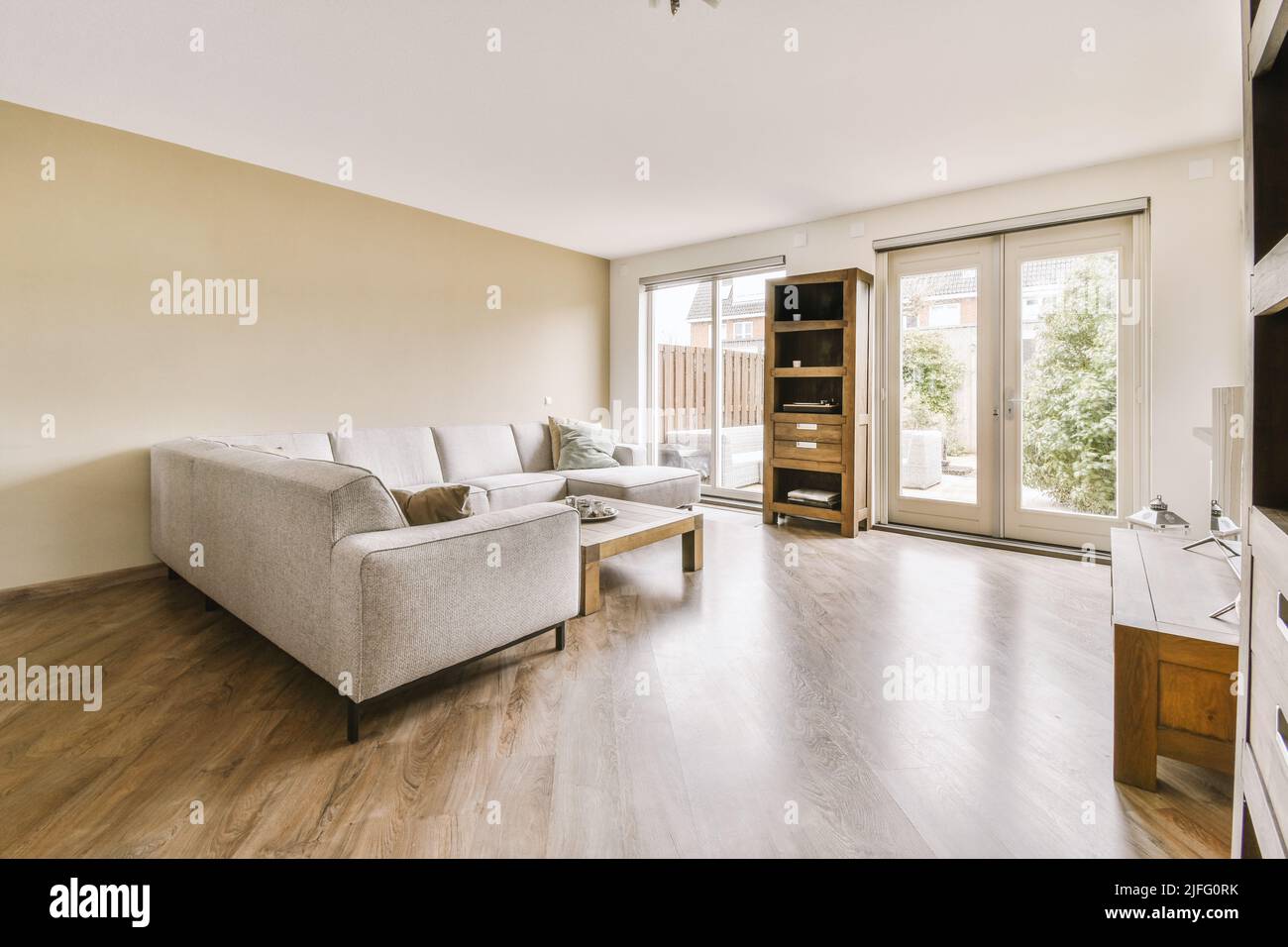 Comfortable sofa with cushions and pouf located near balcony doors and