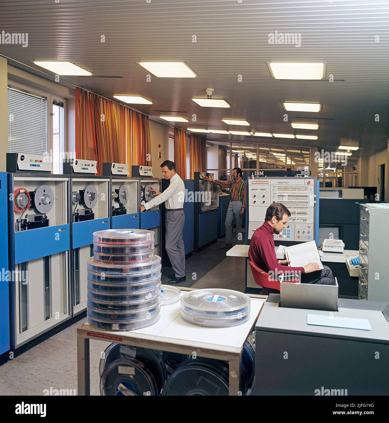 Computer engineering in the 1960s. An interior from the swedish government for employment that handles information with computers, and IBM system 360 with units to read datatapes and terminals to enter and register information. A picture like this represents the first steps towards the digital society where people became social security numbers. IBM system 360 was frequently seen in the american television-series Mad Men. Picture taken 1966. ref CV16-5 Stock Photo