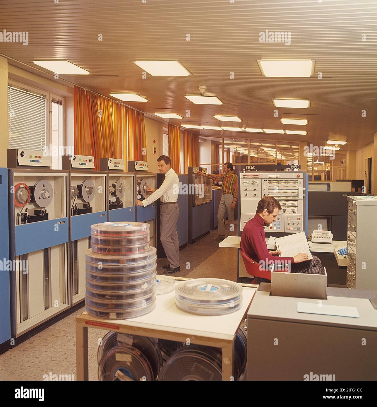 Computer engineering in the 1960s. An interior from the swedish government for employment that handles information with computers, and IBM system 360 with units to read datatapes and terminals to enter and register information. A picture like this represents the first steps towards the digital society where people became social security numbers. IBM system 360 was frequently seen in the american television-series Mad Men. Picture taken 1966. ref CV16-5 Stock Photo
