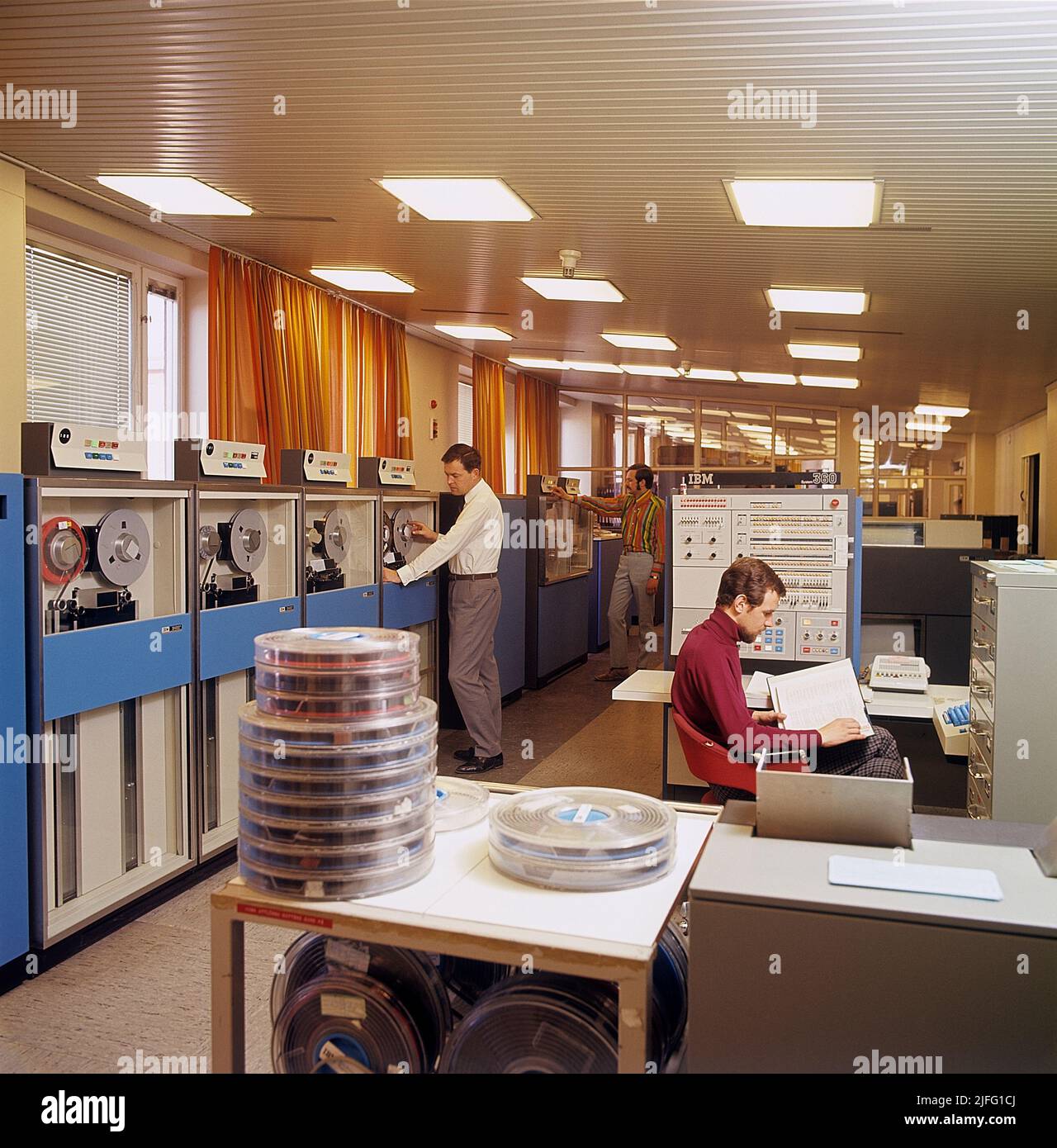 Computer engineering in the 1960s. An interior from the swedish government for employment that handles information with computers, and IBM system 360 with units to read datatapes and terminals to enter and register information. A picture like this represents the first steps towards the digital society where people became social security numbers. IBM system 360 was frequently seen in the american television-series Mad Men. Picture taken 1966. ref CV16-9 Stock Photo