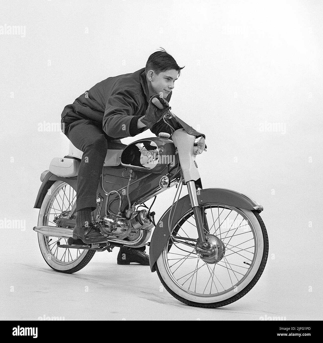 Teenager in the 1960s. A boy in a photographer's studio on a moped, Tomos Sport,  made by the Slovenian company Tomos and exported to Sweden in large numbers in the beginning of the 1960s. With it's long seat and the low handlebars, this sportsmodell was considered the best and toughest looking moped. Sweden 1961 Kristoffersson ref CX85-1 Stock Photo