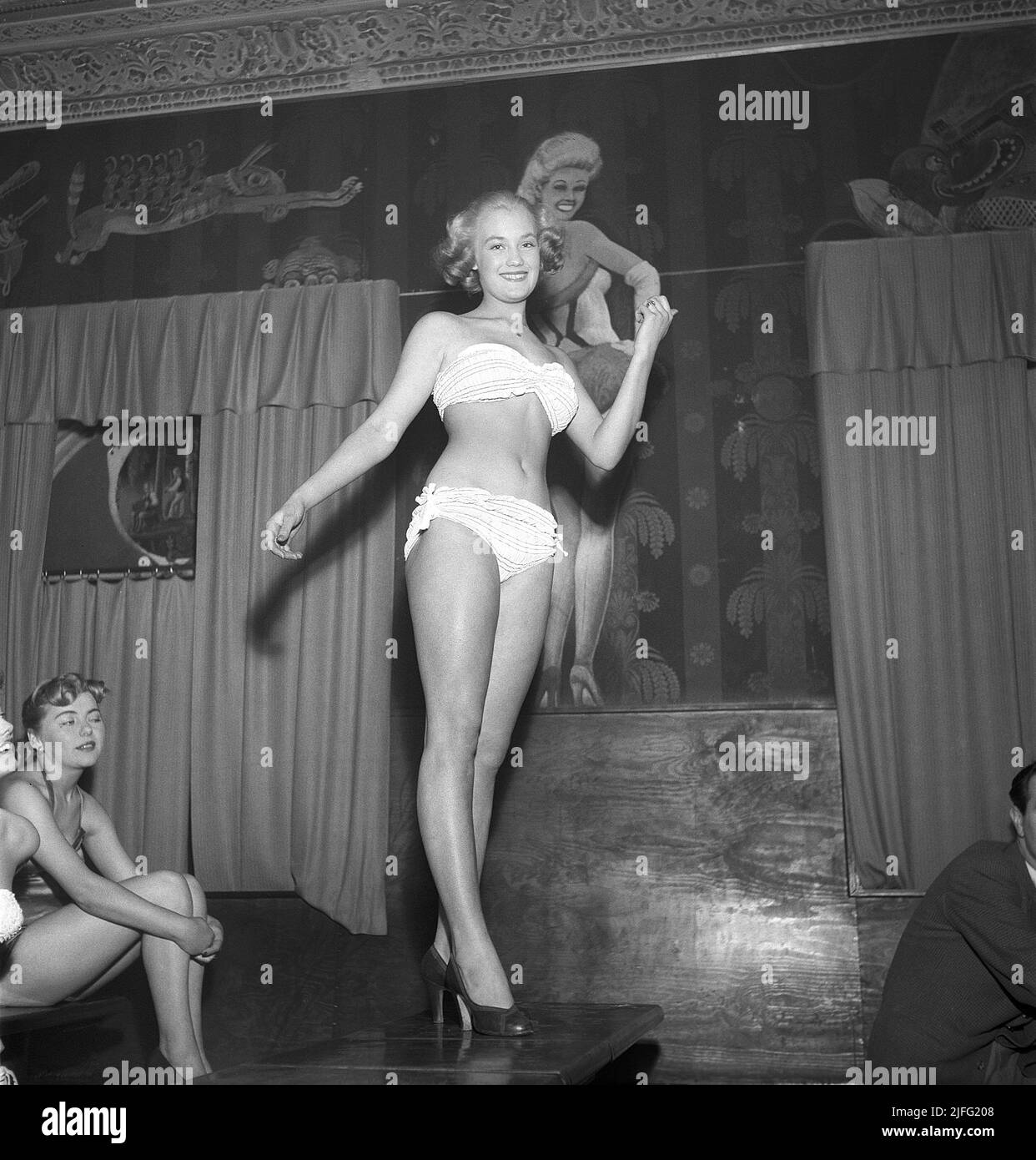 Woman of the 1950s. One of the contestants in the beauty contest is Monika Larsson and she is pictured in her bikini during the contest. On the wall behind her is a painting of the american actress Betty Grable, probably the most famous female moviestar during the time of WWII. She was the most popular pin-up girl.  Sweden 1953. Kristoffersson ref BL33-5 Stock Photo