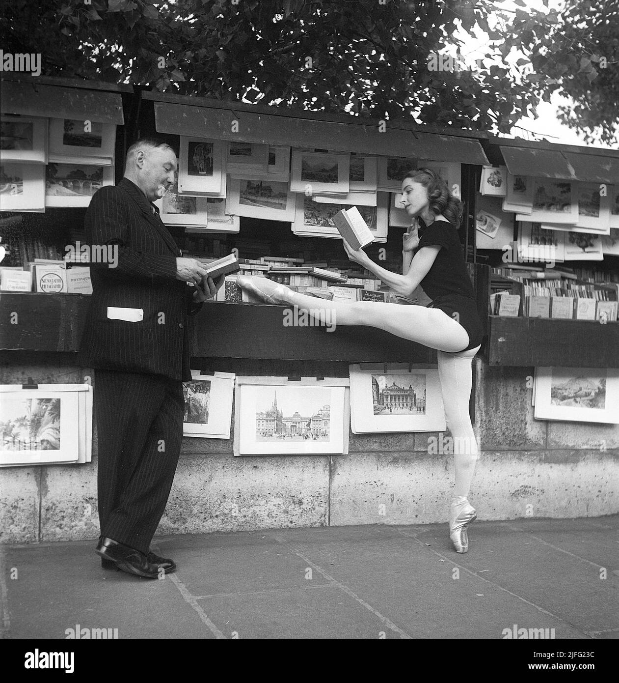 Ballerina in Paris 1952. Ellen Rasch, 1920-2015 pictured in Paris in her dancing outfit standing on one toe reading a book off a street merchants stand. Paris 1952 Kristoffersson ref BD27-5 Stock Photo
