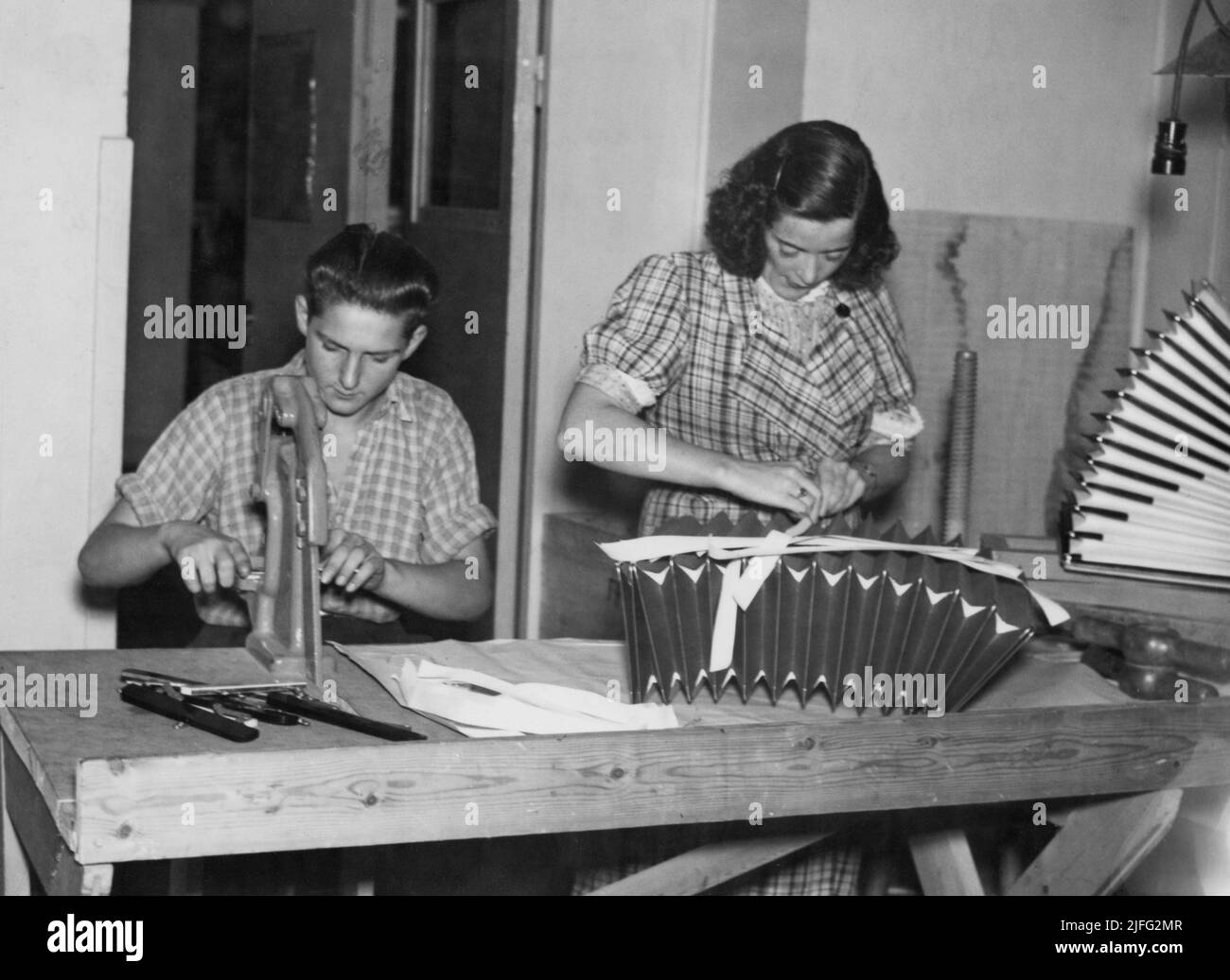 Accordion manufacturing. Interior of Ragnar Sundquists accordion factory in Stockholm. He was one of the most popular accordion players during the first half of the 20the century. He started manufacturing accordions that beared his name somewhat; Raggie Special. Picture shows a man and woman in the factory 1939. Stock Photo